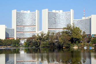 Hinter einem See ranken einige Hochhäuser in die Luft.