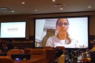 Nujeen Mustafa, eine junge Syrerin mit Behinderung, hält eine Rede beim Side Event der UN Generalversammlung zum Thema: "Die Umsetzung der politischen Erklärung zur Verstärkung des Schutzes der Zivilbevölkerung vor dem Einsatz von Explosivwaffen in bewohnten Gebieten (EWIPA)". Das Bild zeigt sie auf dem Bildschirm, währed sie ihre rede hält.
