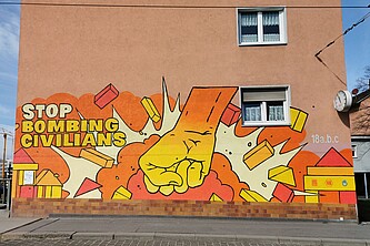 Graffiti: Eine Faust zerschmettert ein Wohngebiet. Stop Bombing Civilians.