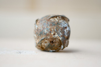 submunition-streumunition-blu26 Die Submunition ist ein runder metallischer Ball, schmutzig und rostig.