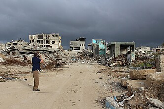 Ein Mann fotografiert einen völlig zerstörten Gebäudekomplex.